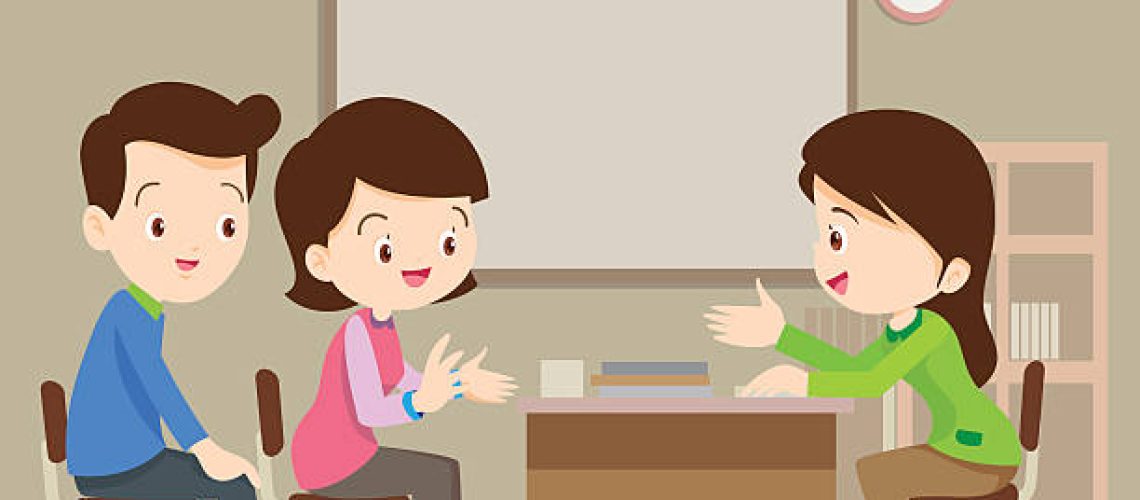 Parent meeting with teacher in classroom.